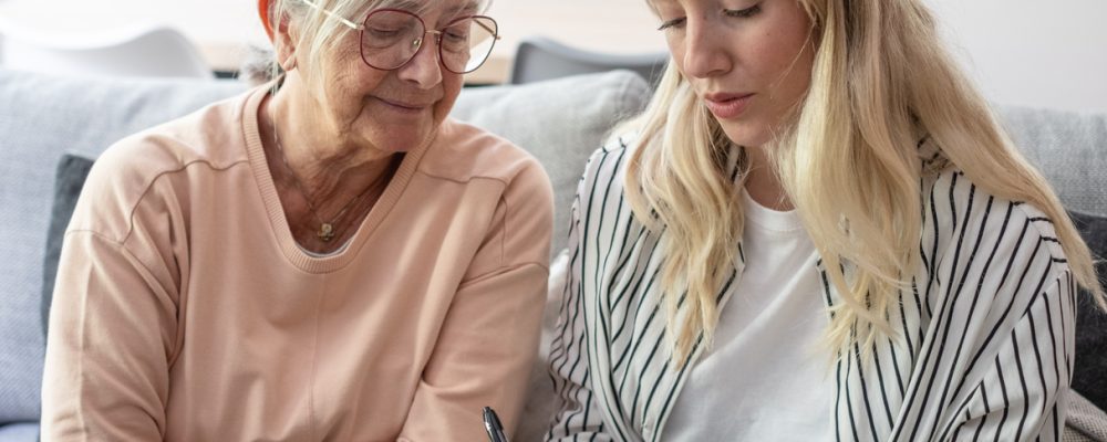 Adult daughter and senior mother writing down questions to ask on a senior living tour.