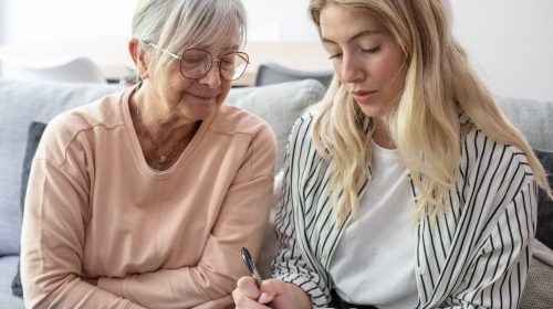 Adult daughter and senior mother writing down questions to ask on a senior living tour.