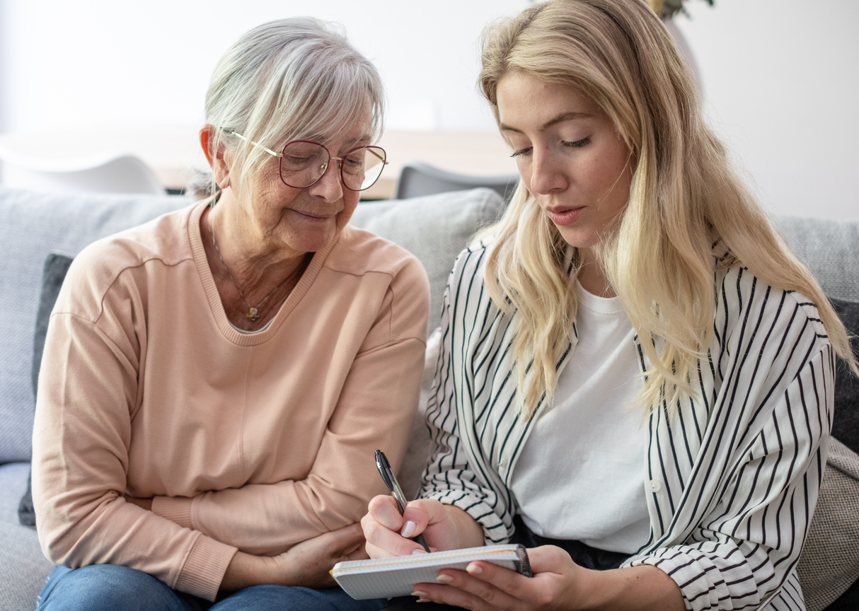 Adult daughter and senior mother writing down questions to ask on a senior living tour.