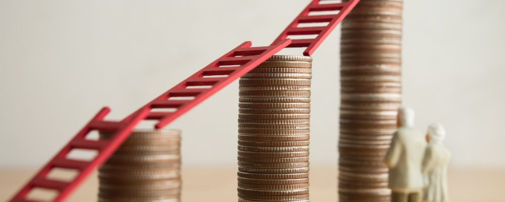 Senior couple facing climbing coin stacks and ladders, representing how to pay for assisted living.