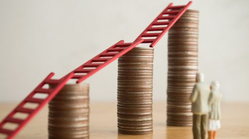 Senior couple facing climbing coin stacks and ladders, representing how to pay for assisted living.
